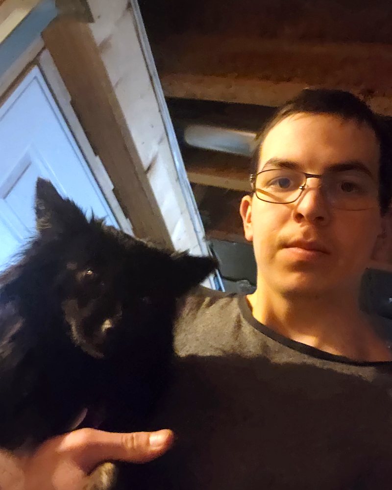 Eugene holding a small black dog.