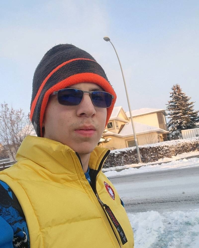 Eugene outside on a snowy Calgary street in a toque and a yellow vest.